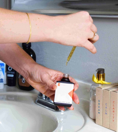 person getting ready by sink with many makeup and skincare products