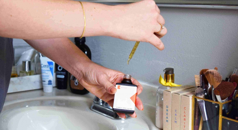 person getting ready by sink with many makeup and skincare products