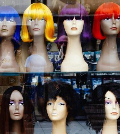 wigs with different hairstyles in a window