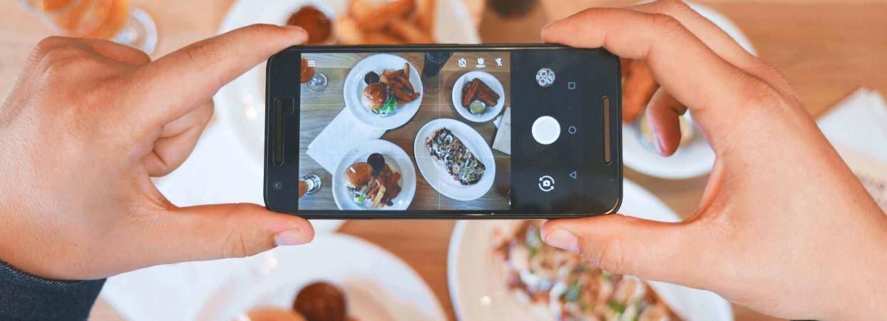 food influencer taking a picture of food on a table