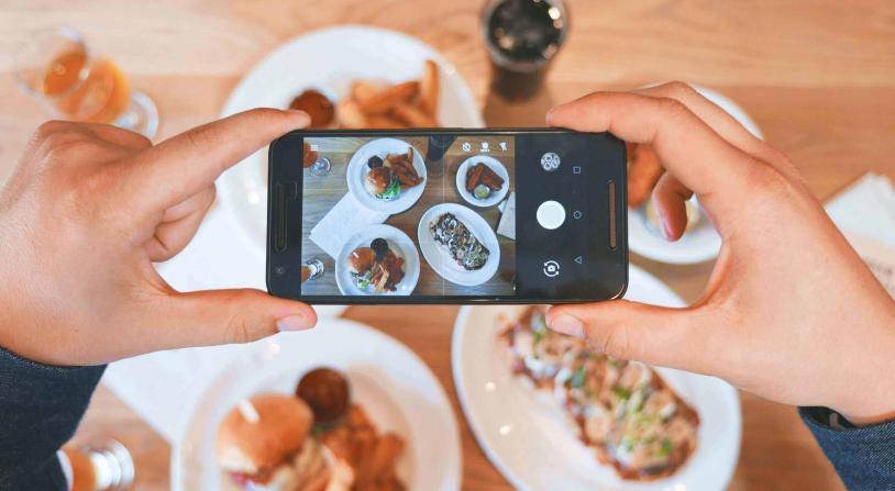 food influencer taking a picture of food on a table