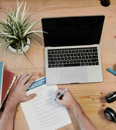 hand holding notepad next to computer and marketing book