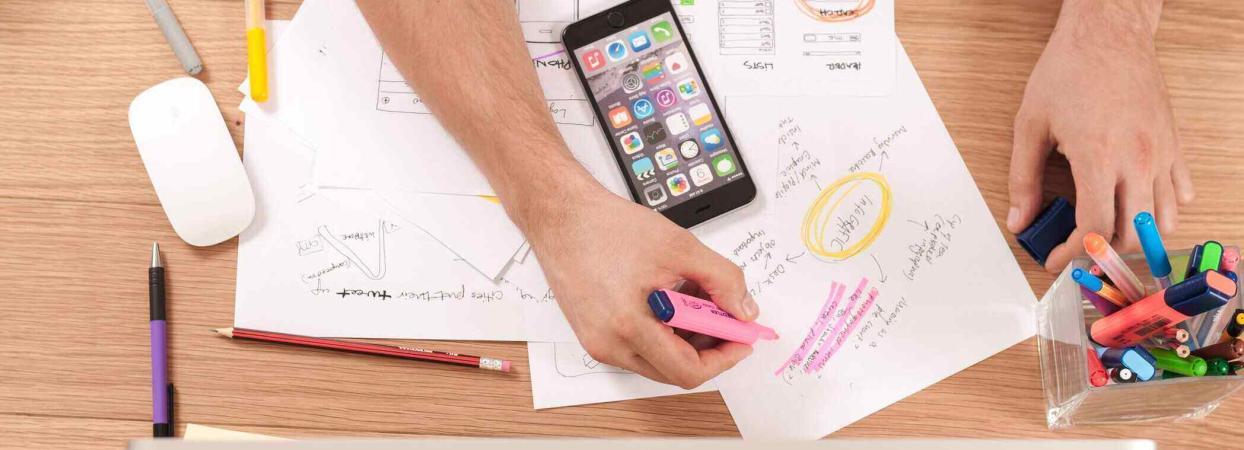 person writing on a paper with a phone