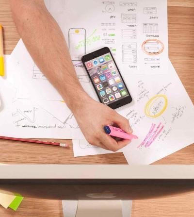 person writing on a paper with a phone