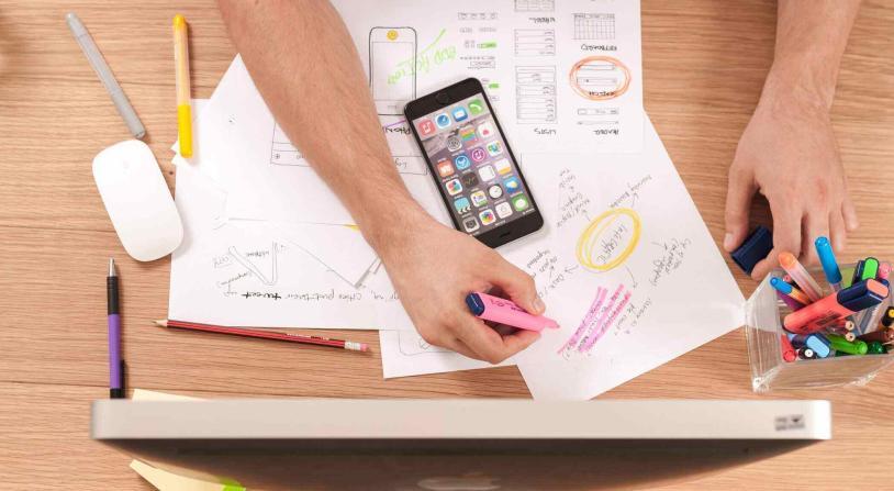 person writing on a paper with a phone